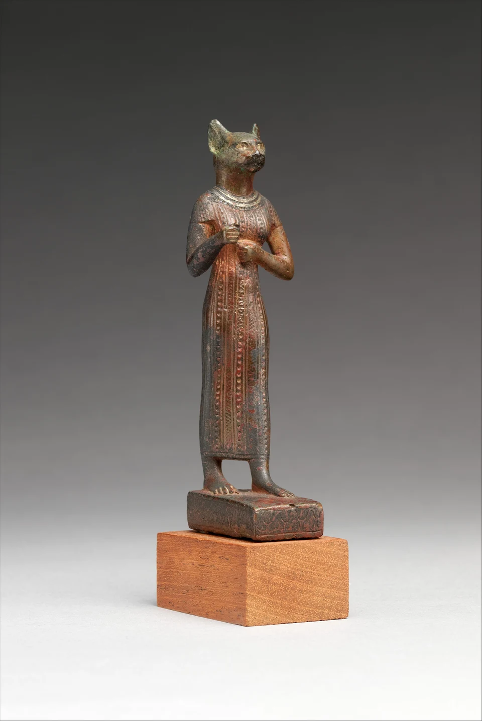 Katzenköpfige stehende Bronzefigur mit langem gemustertem Gewand und fehlenden Handattributen.