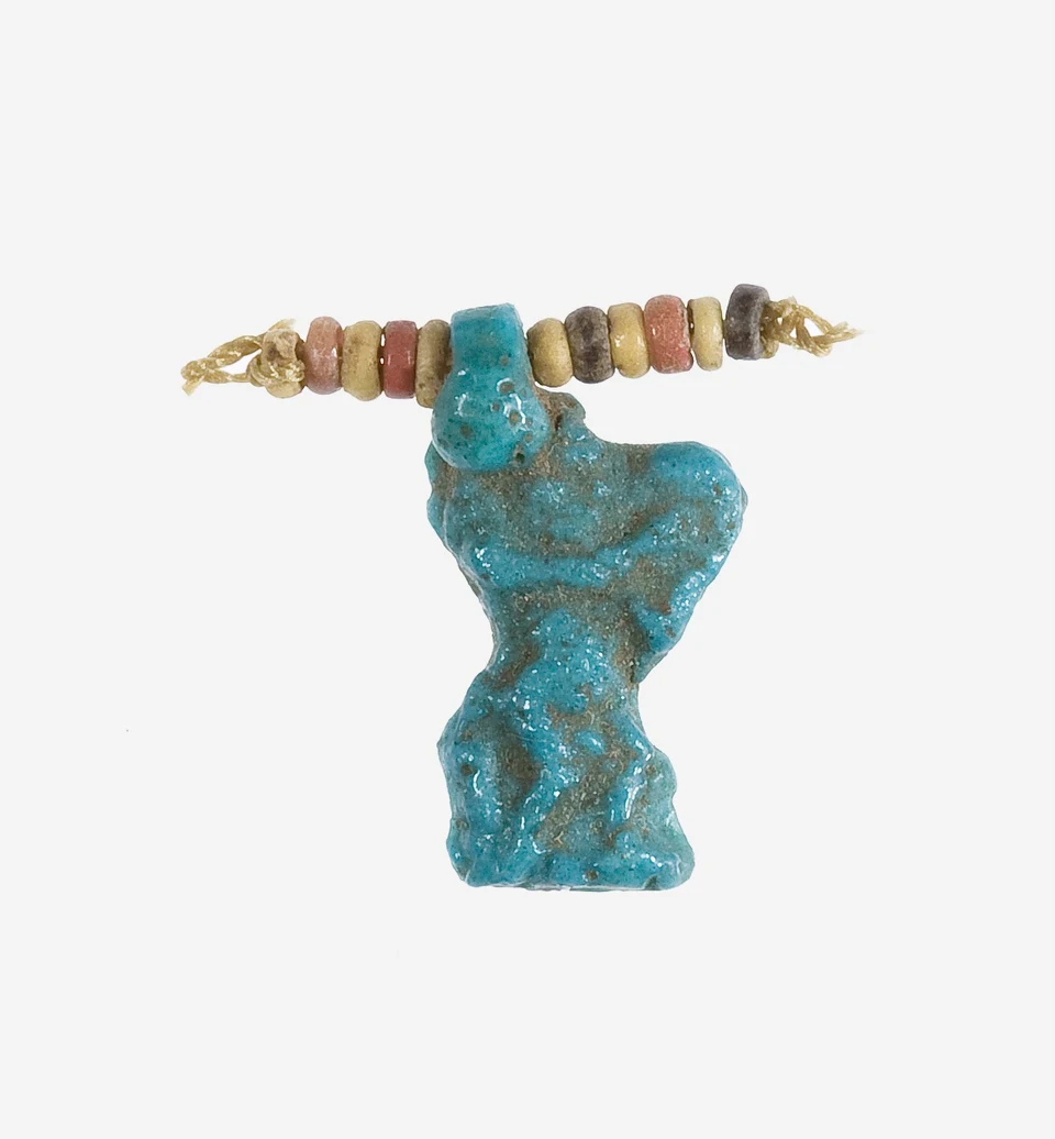 Kleines blaues Bes-Amulett an erhaltenem Faden mit zehn farbigen Perlen vor hellem Grund.