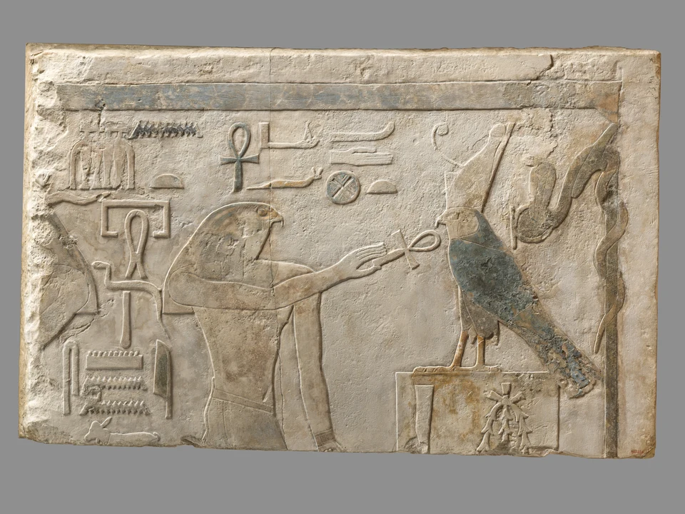 Breiter bemalter Kalksteinsturz: links ein nur teilweise erhaltener widderköpfiger Gott, rechts Horus mit Lebenszeichen vor dem Königsnamen.
