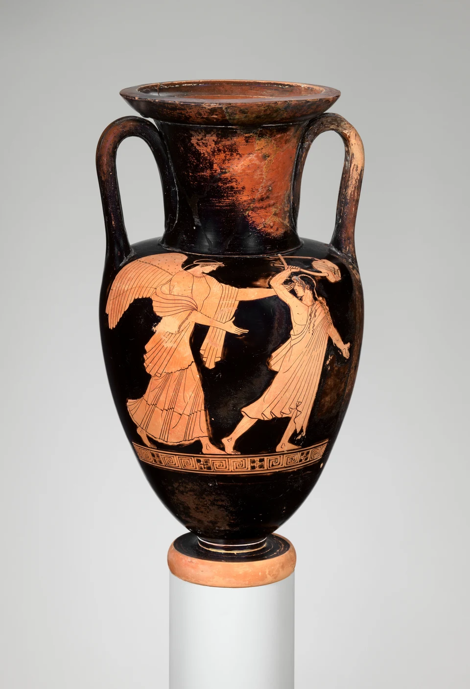 Rotfigurige attische Amphora vor grauem Hintergrund: eine geflügelte Frau greift nach einem rückwärts weichenden jungen Mann.
