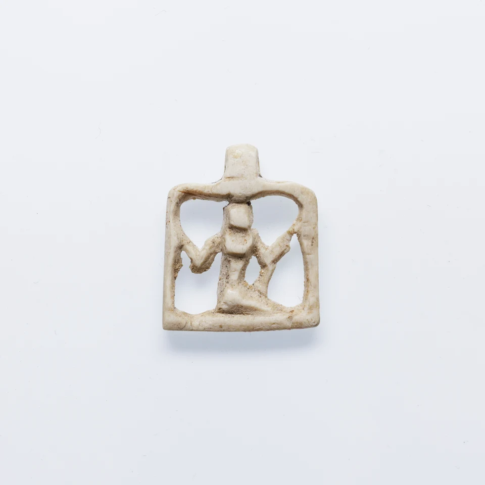 Kleines helles Amulett mit kniender, stilisierter Heh-Gestalt in einem rechteckigen Rahmen.