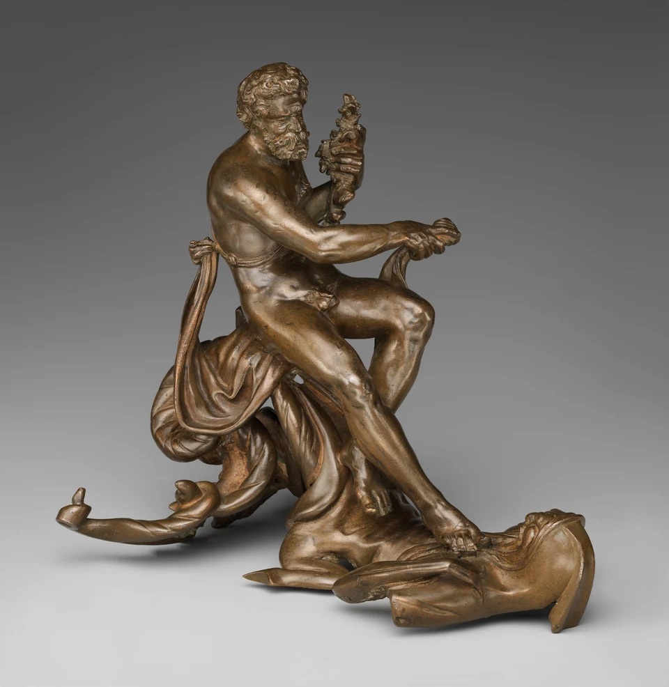 Bronzegruppe: eine sitzende kräftige Männerfigur hält eine andere Gestalt am Boden nieder; in seinen Händen liegen kleine Formen.