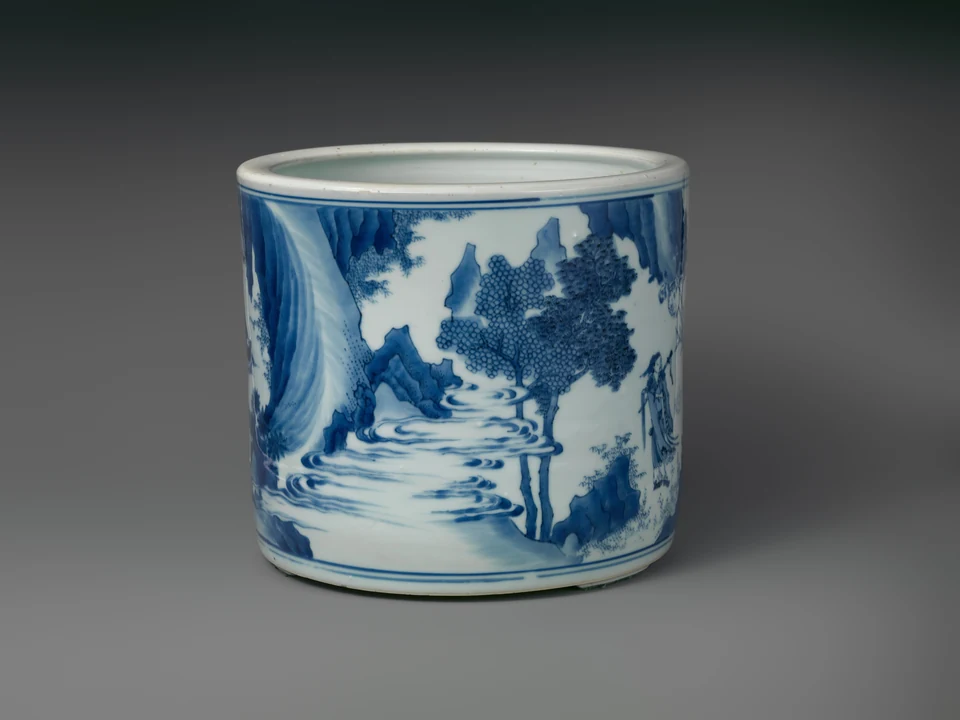 Gedrehte Ansicht des Pinselbehälters mit blauen Wasserlinien, Felsen, Baum und angeschnittenen Gewandfiguren an den Rändern.