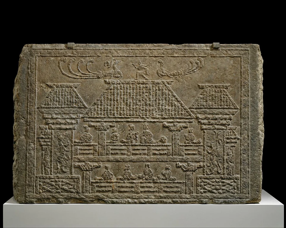 Steinrelief mit zwei Ebenen sitzender Figuren in einer Pavillonarchitektur und langschwänzigen Vögeln darüber.