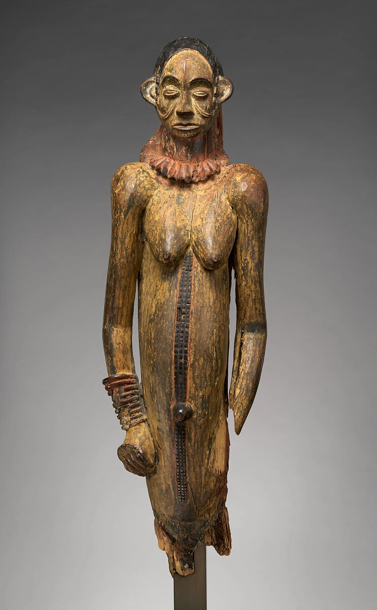 Eine geschnitzte weibliche Holzfigur mit Halskette, langem Rumpf und erhaltenen Farbresten; Beine und Teile eines Arms fehlen.