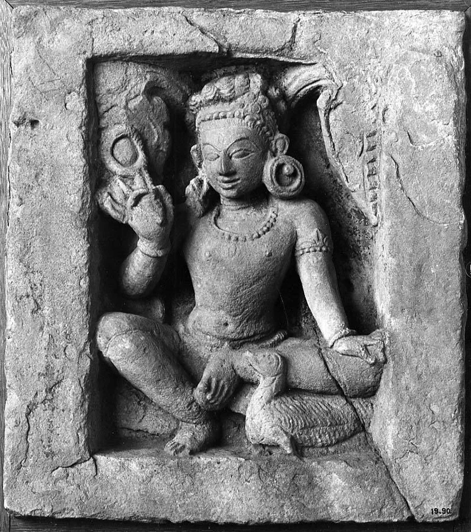 Schwarzweißfoto eines beschädigten Sandsteinreliefs: sitzende Figur mit erhobener Schlaufe in einer Steinrahmung; darunter ein Vogel mit langem Hals.