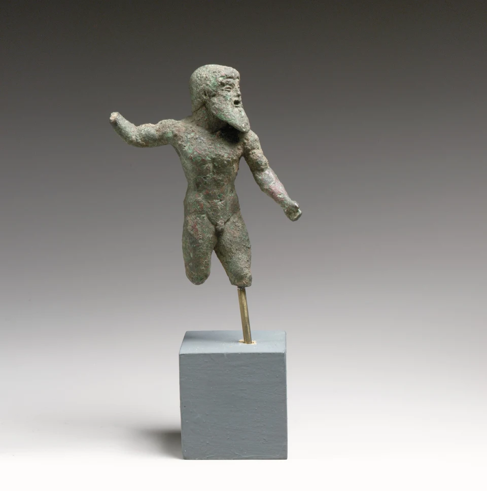 Bronzene bärtige Männerfigur mit erhobenem rechtem Arm und gesenktem linkem Arm. Die rechte Hand und Teile der Unterschenkel fehlen; darunter ein moderner Sockel.